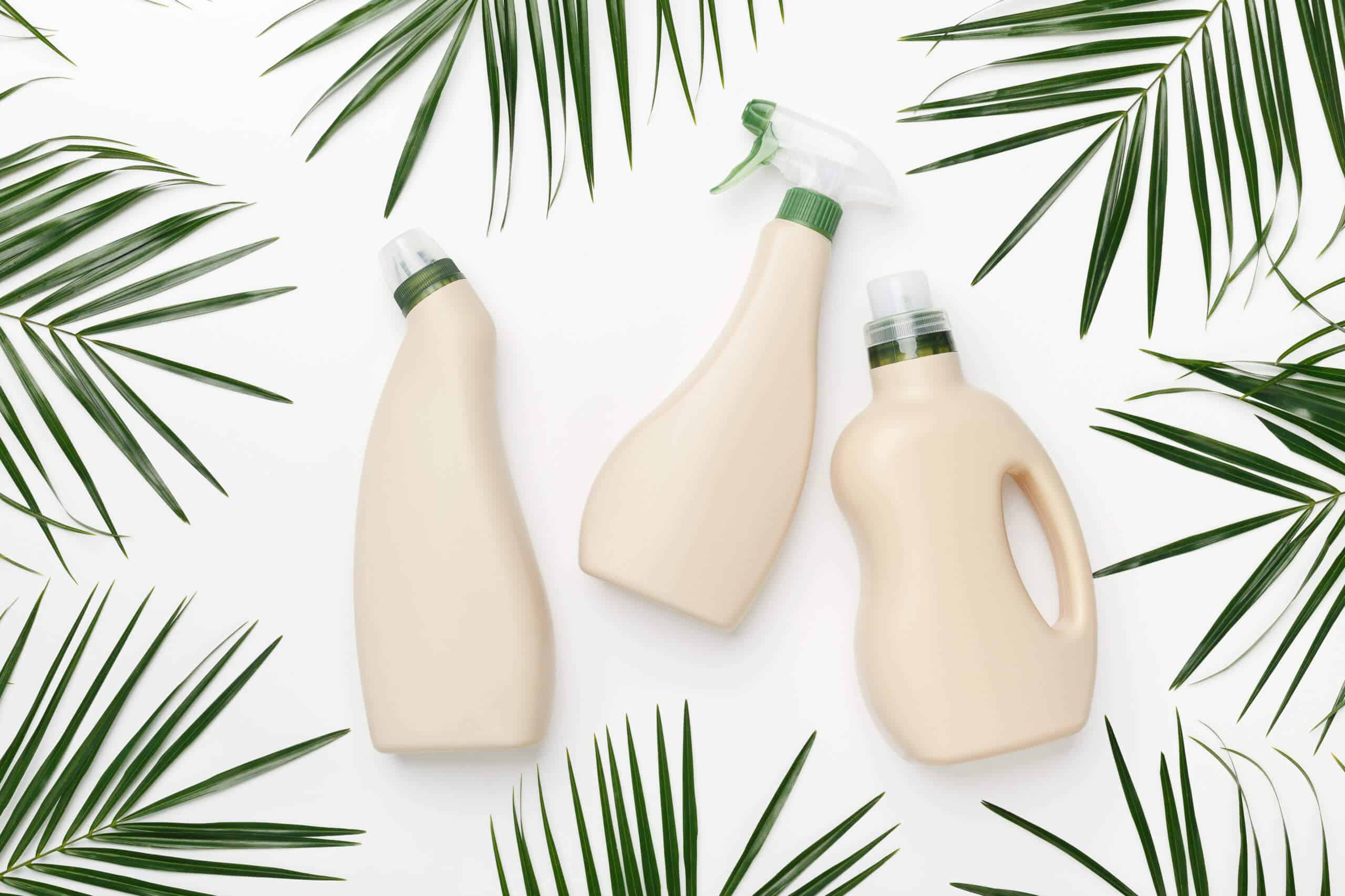 Bio-Design von Plastikflaschenverpackungen für Wasch- und Reinigungsmittel zwischen natürlichen grünen Blättern auf weißem Hintergrund