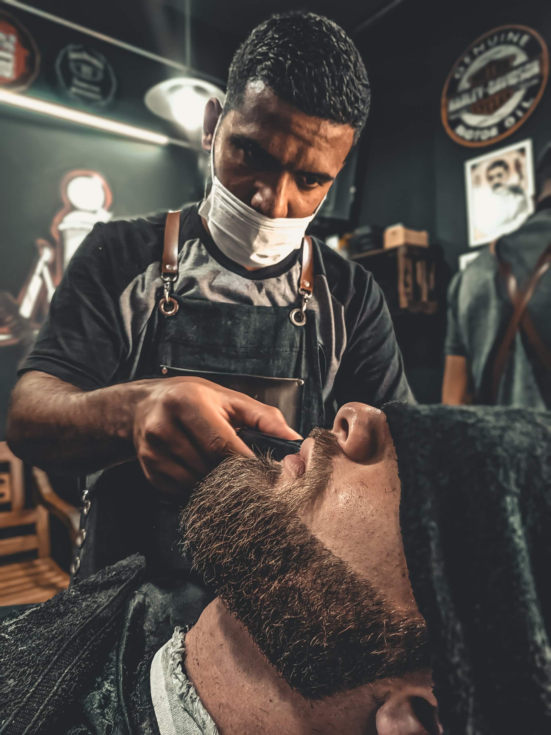 Male hairdresser cutting hair to hipster senior client while wearing face surgical mask