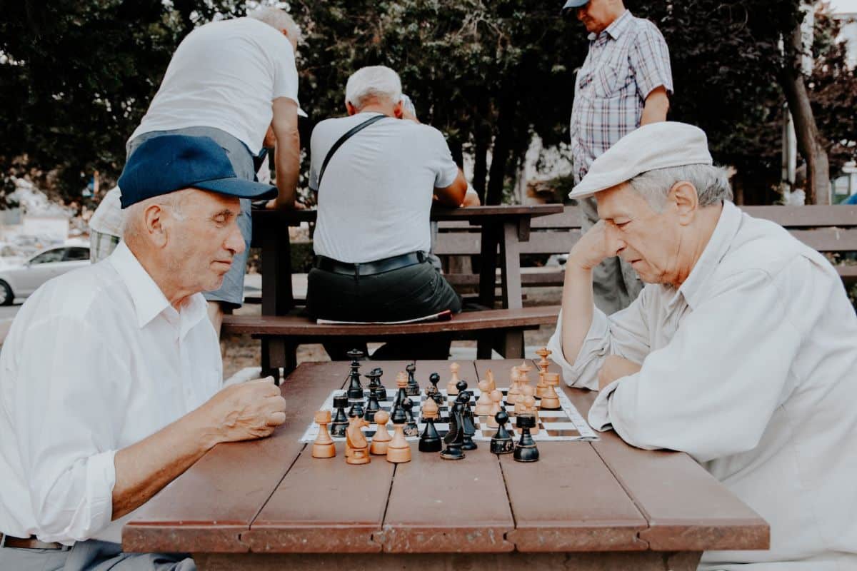 Zwei ältere Männer, tief vertieft in eine Partie Schach, planen ihre nächsten Züge.