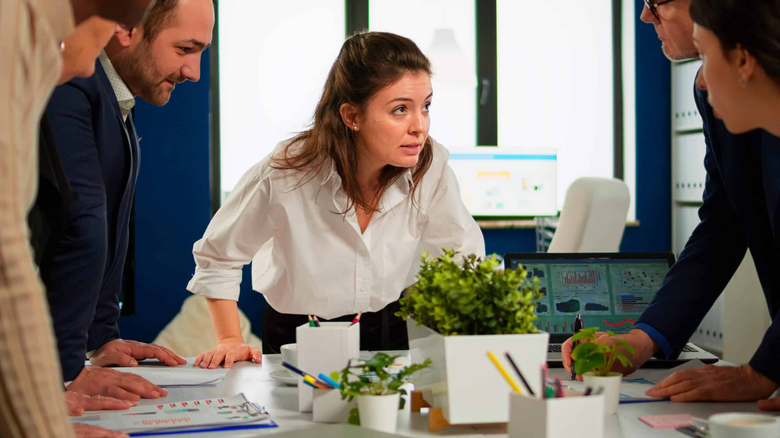 Brand manager asking for explication from employee in start up office discussion, Diverse team of business people analyzing company financial reports from computer.