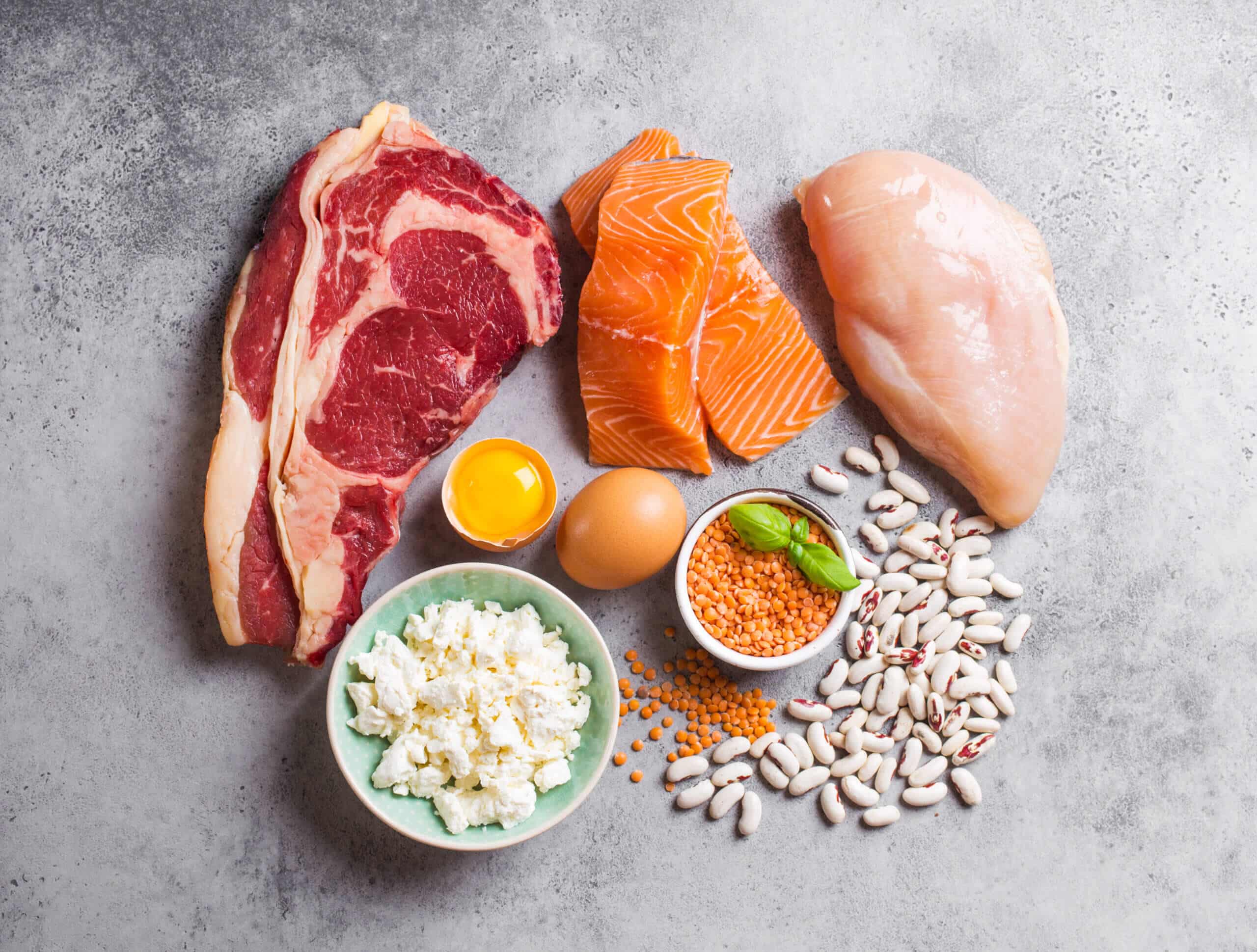 Sortiment natürlicher Proteinquellen aus Lebensmitteln: Fleisch, Fisch, Huhn, Milchprodukte, Eier, Bohnen. Konzept für Ernährung, gesunde Ernährung, Wellness, Bodybuilding, Draufsicht, Steinhintergrund