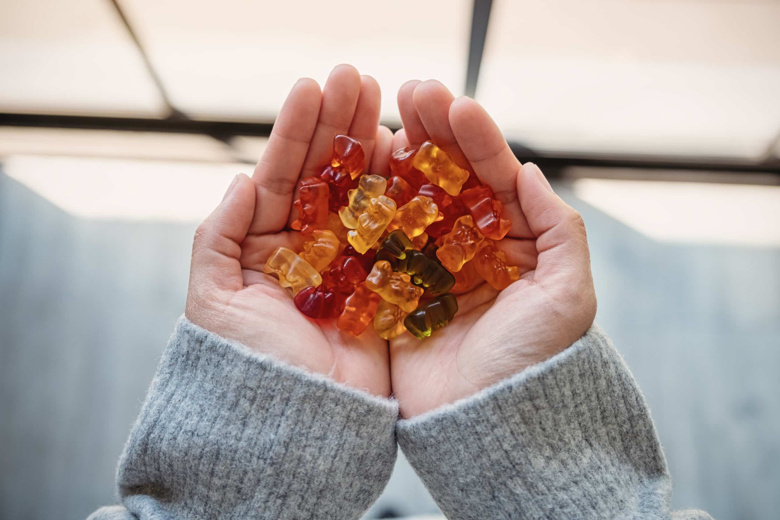 Top view image of a woman holding colorful jelly gummy bears in hands