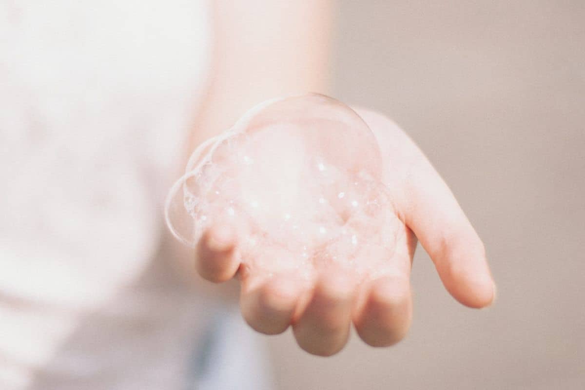 A hand covered in a layer of rich, sudsy foam, highlighting the action of washing or applying a foaming product.