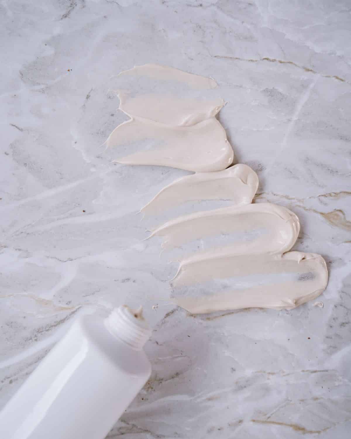 Nahaufnahme einer Bodylotion-Flasche oder eines Behälters vor hellem Hintergrund.