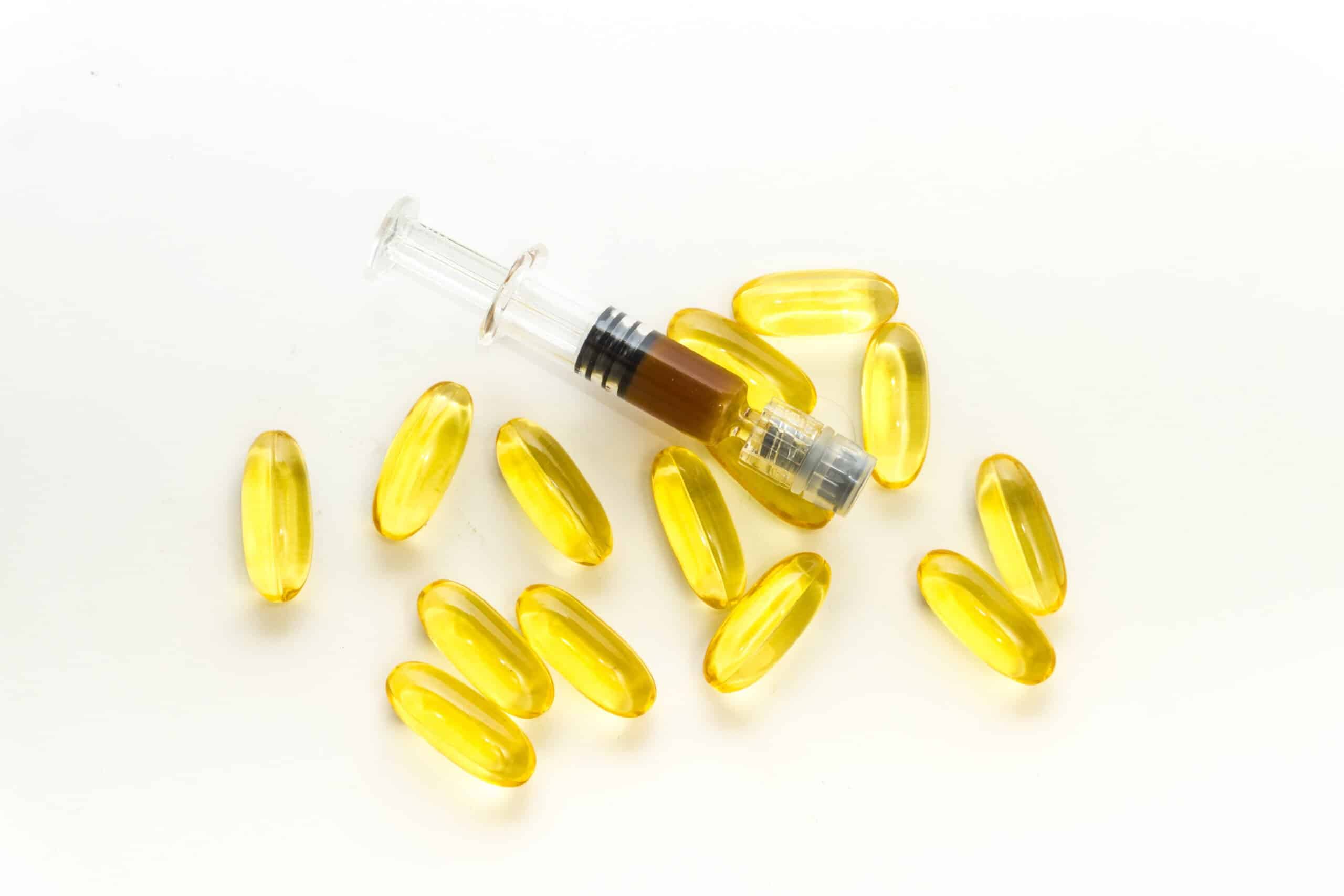 Cannabidiol CBD clear oil capsules and full spectrum Hemp paste on wooden table