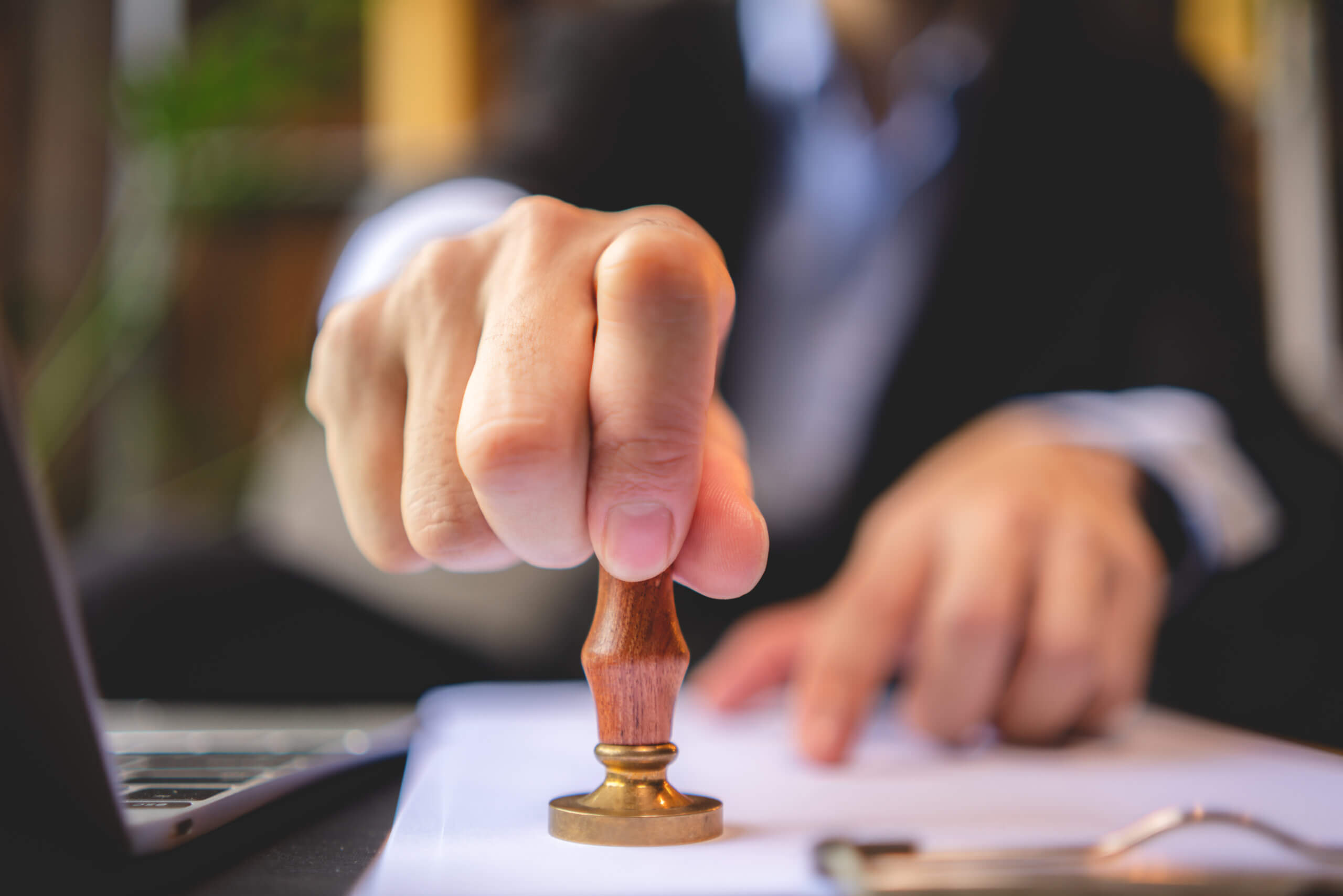 Close-up of a person's hand stamping with approved stamp on approval certificate document public paper at desk, notary or business people work from home, isolated for certifications for private label 