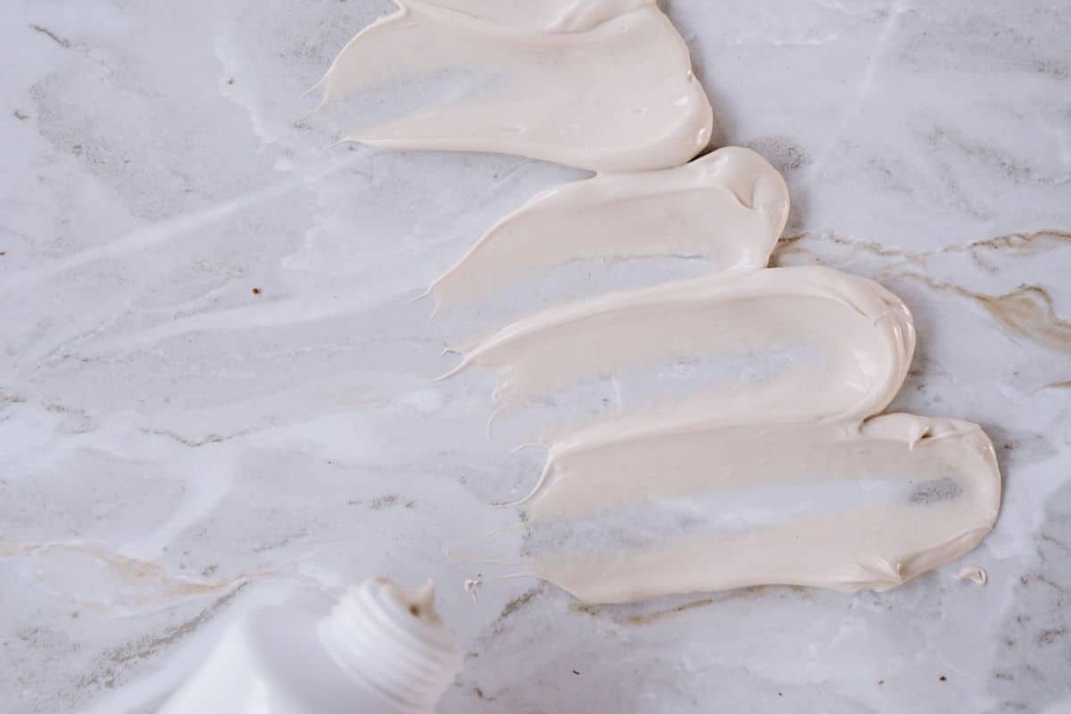 A squeeze tube of face cream, its cap open revealing a hint of the product, set on a neutral background.
