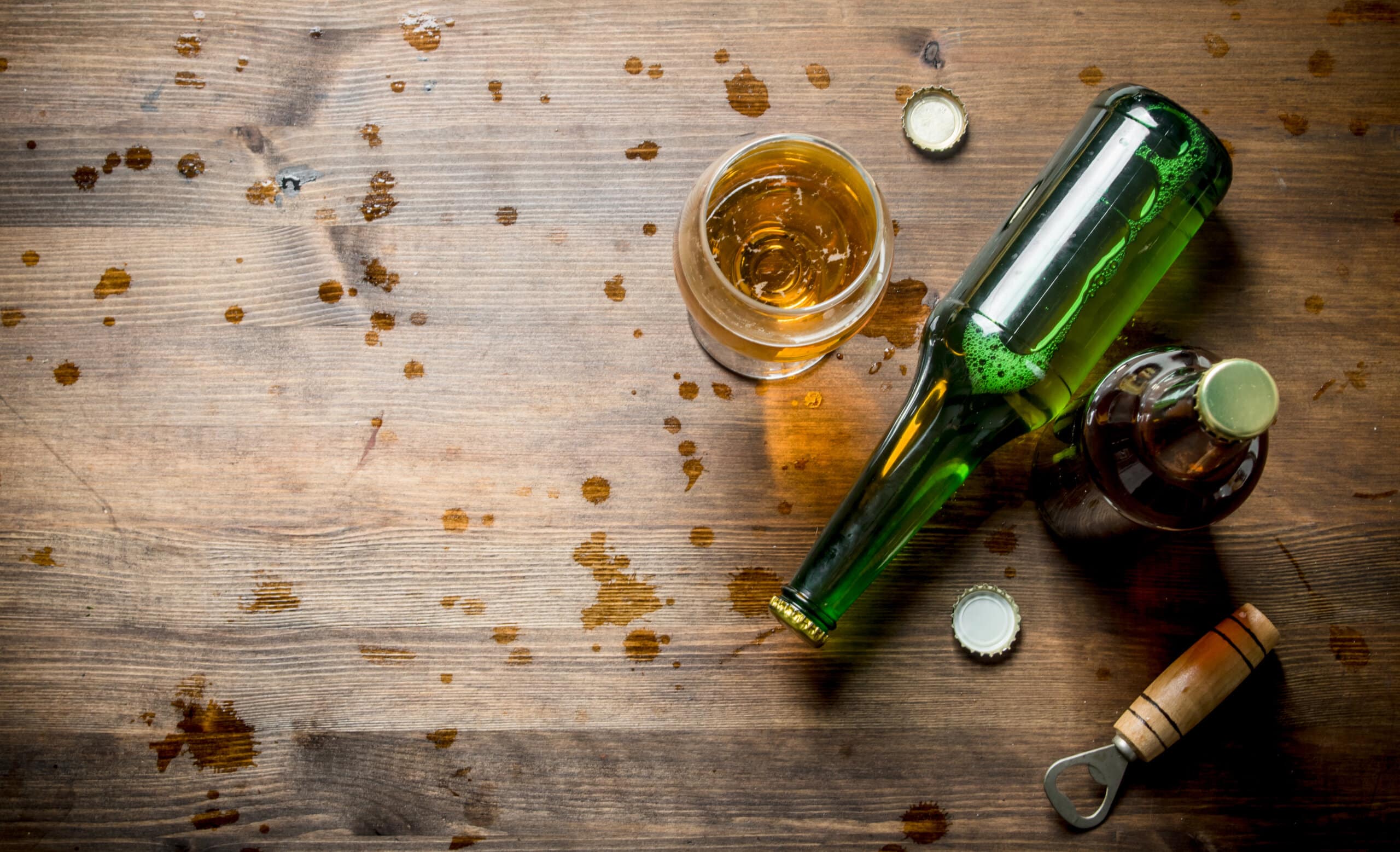 Beer and beer drops. On wooden background
