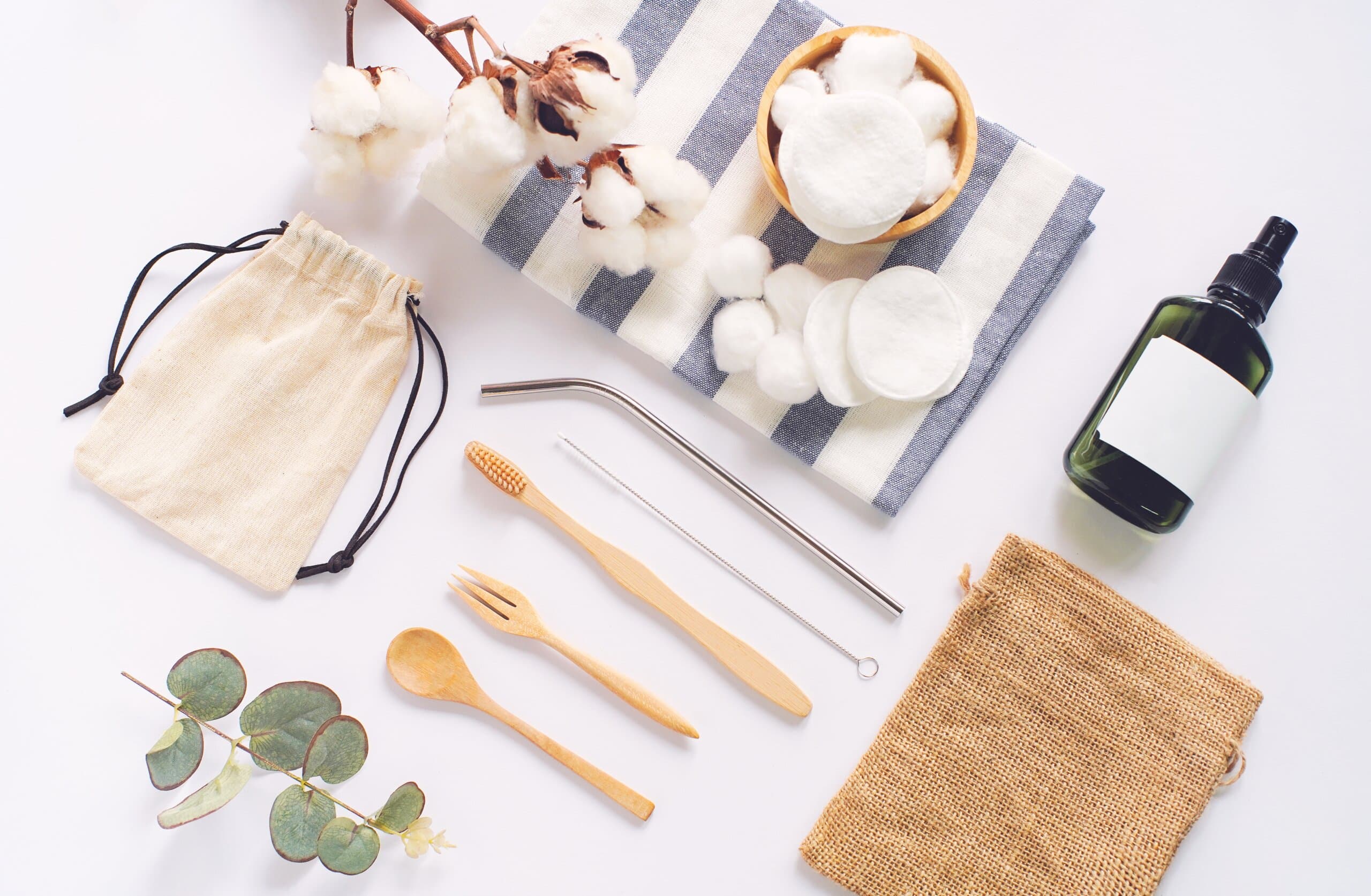 Flat lay of sustainable products, wooden spoon, stainless straw, organic cosmetic and natural cotton on white background, eco friendly and zero waste concept