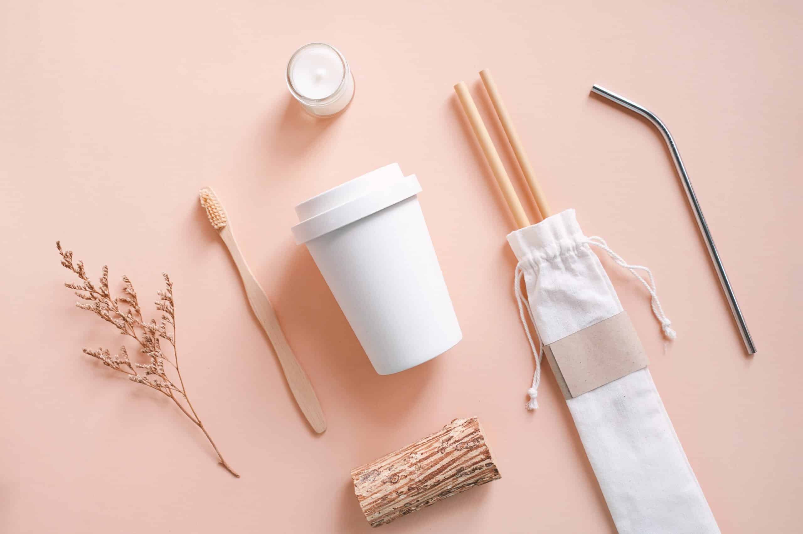 Flat lay of sustainable products, bamboo toothbrush, straw in sack bag with glass and organic candle on autumn color background, eco friendly and zero waste concept