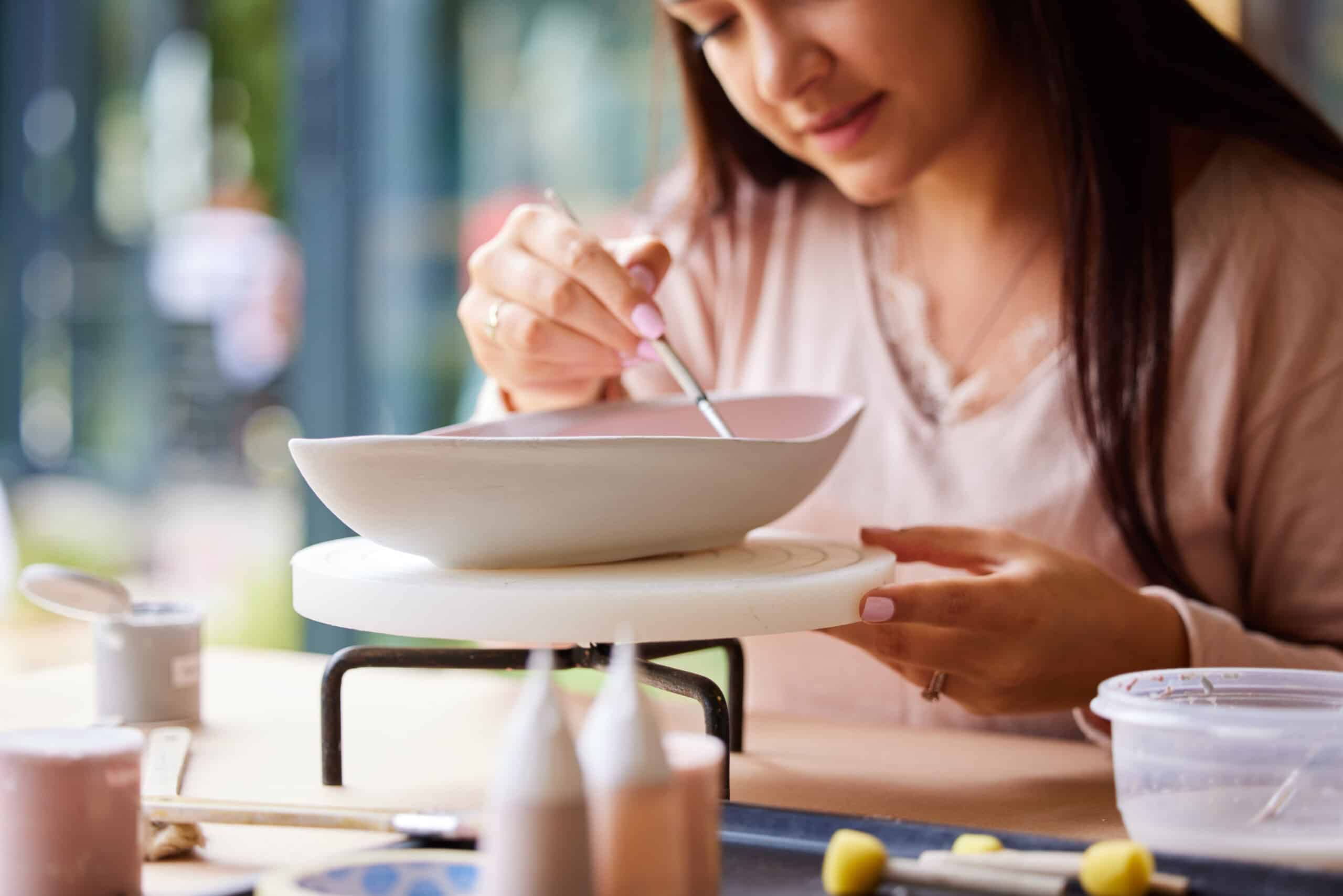 Cropped shot of a young woman painting ceramics in an art studio.