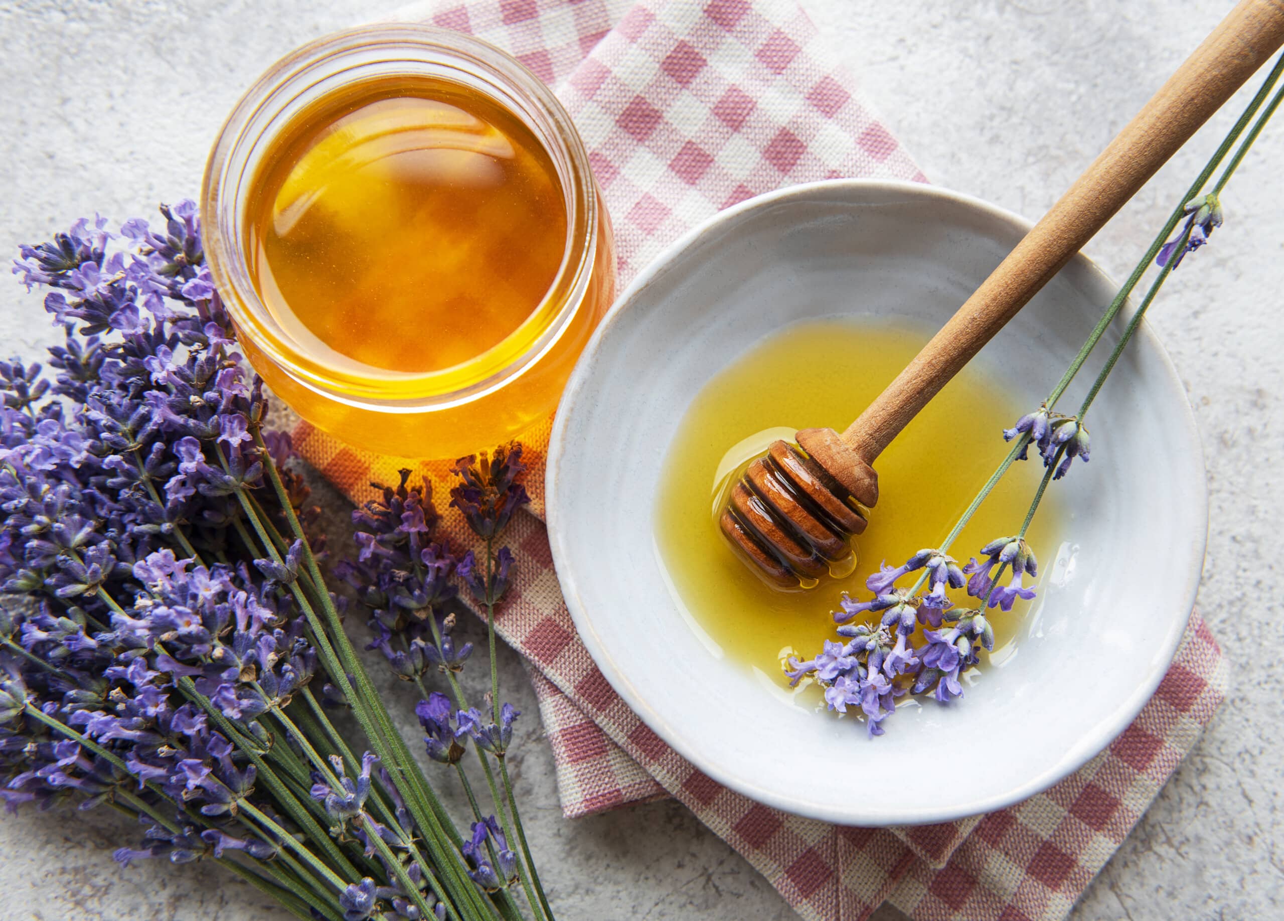 Jar with honey and fresh lavender flowers on a concrete background
