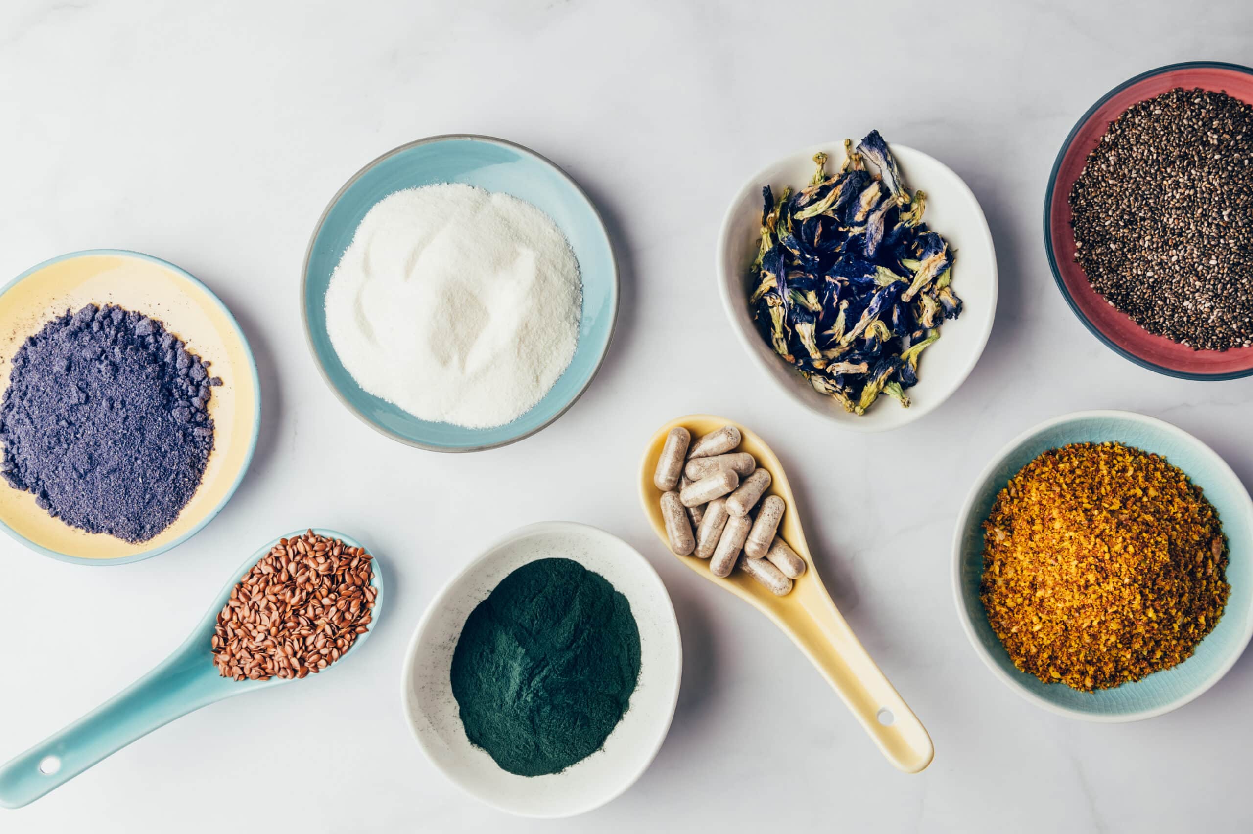 Variety of healthy food supplements such as blue matcha, butterfly pea flowers, collagen powder, spirulina powder, vitamins for vegans and vegetarians, flax and chia seeds,