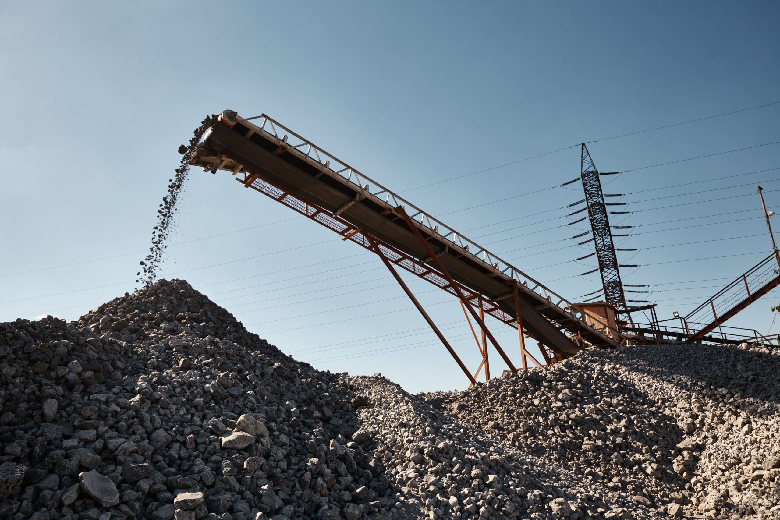 Working conveyor belt on slag transportation and loading. Heavy industrial metallurgical landscape with power lines on background