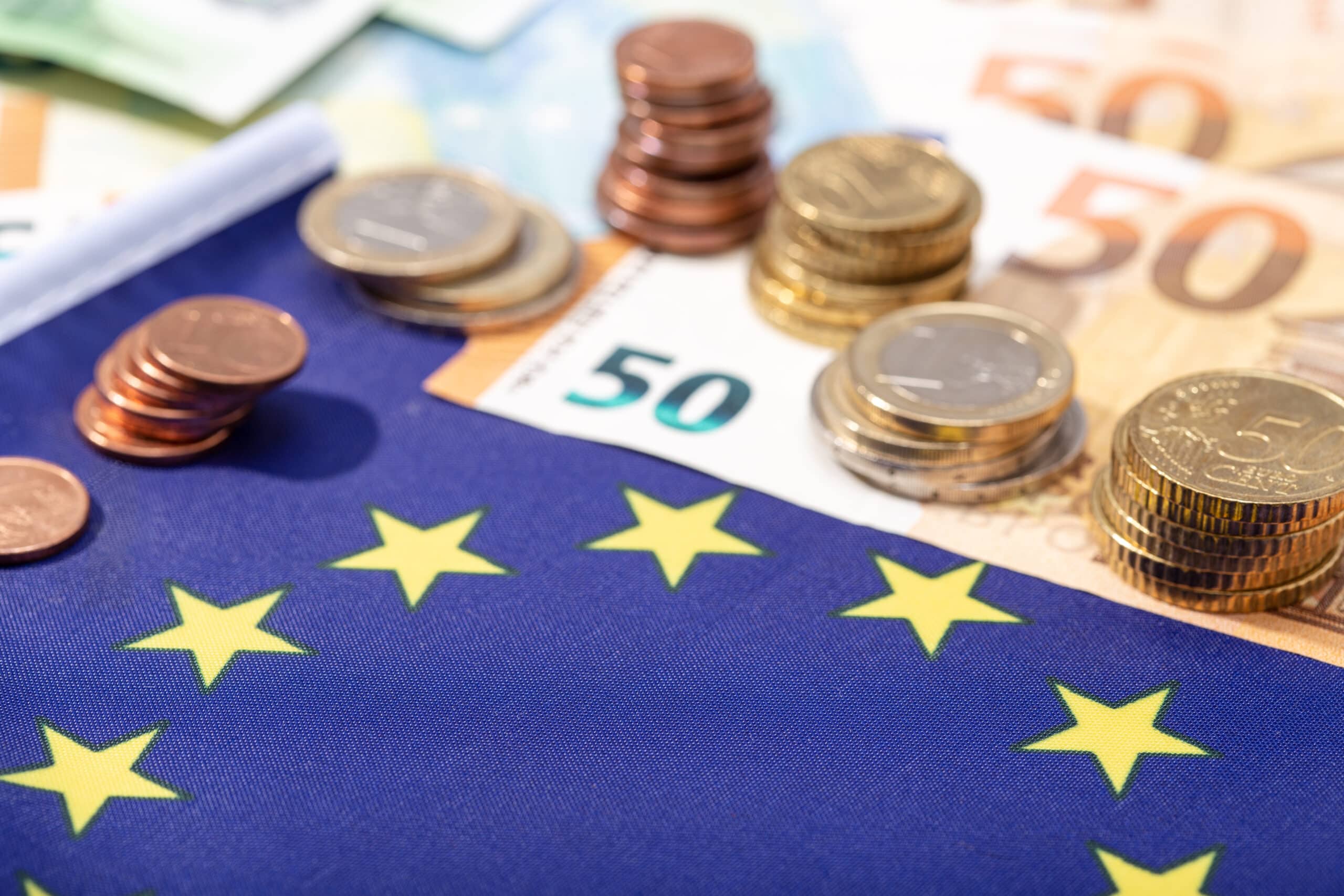 European Union financial stimulus on coronavirus Covid-19 pandemic concept. European Union flag with euro bills and coins