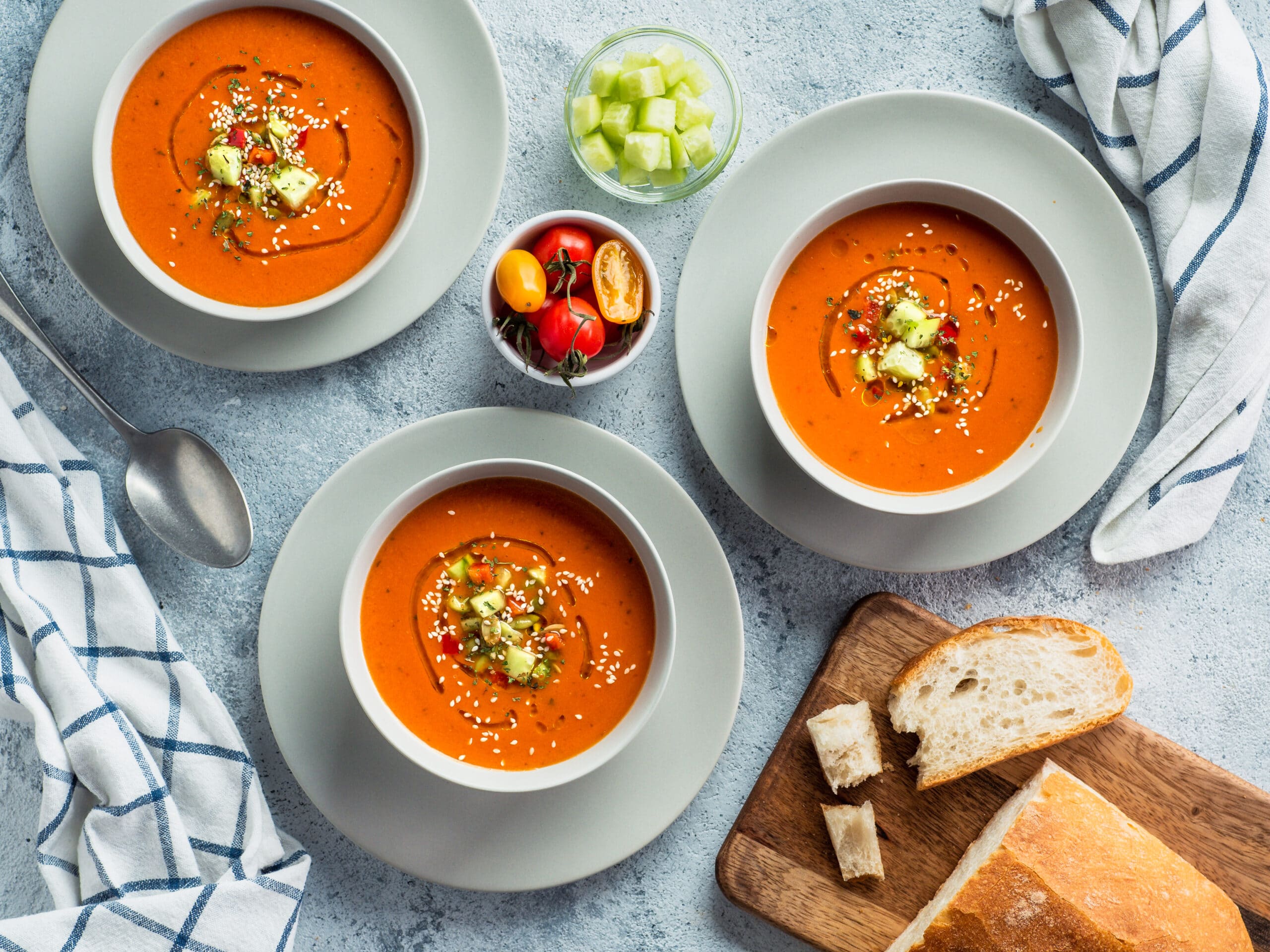 Gaspacho soup on white marble tabletop. Three bowls of traditional spanish cold soup puree gaspacho or gazpacho on light gray or white marble background. Top view or flat lay.
