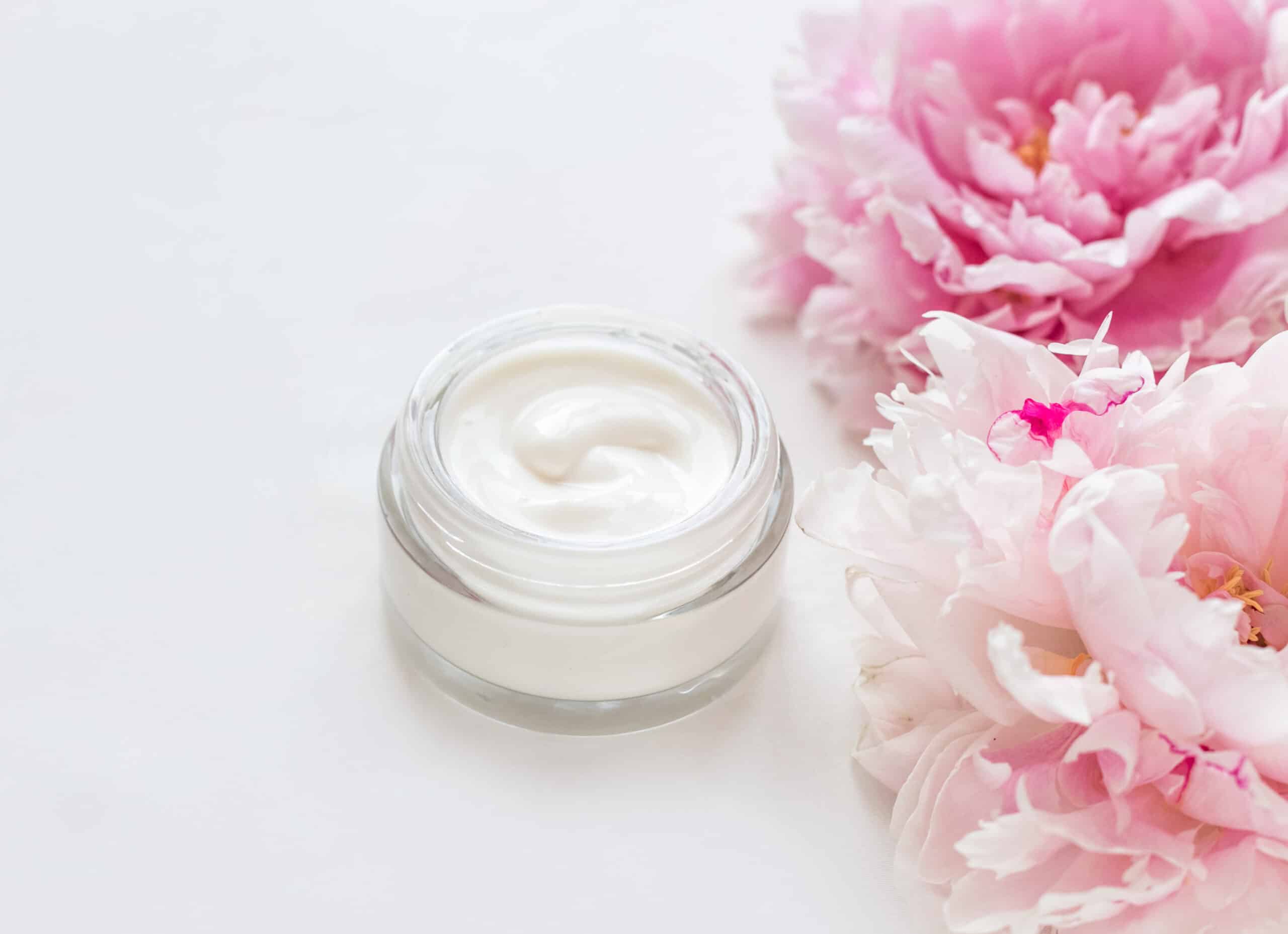 Jar of skin care cream and pink peonies