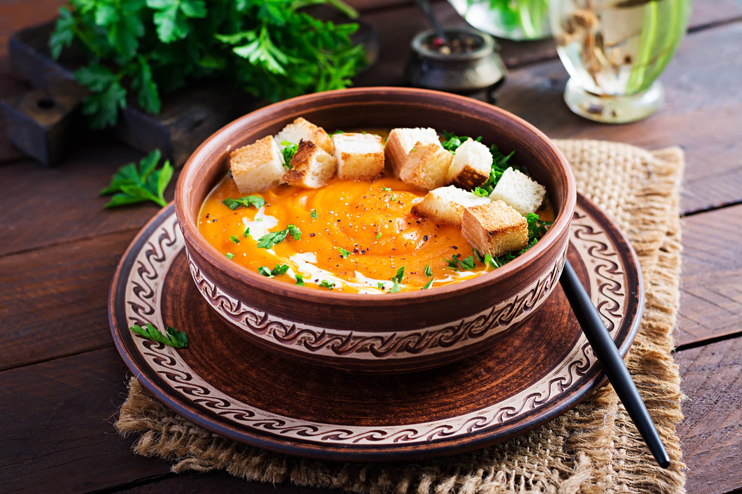 Pumpkin vegan soups in a bowl served with croutons and parsley. Vegan diet soup. Vegetarian food.