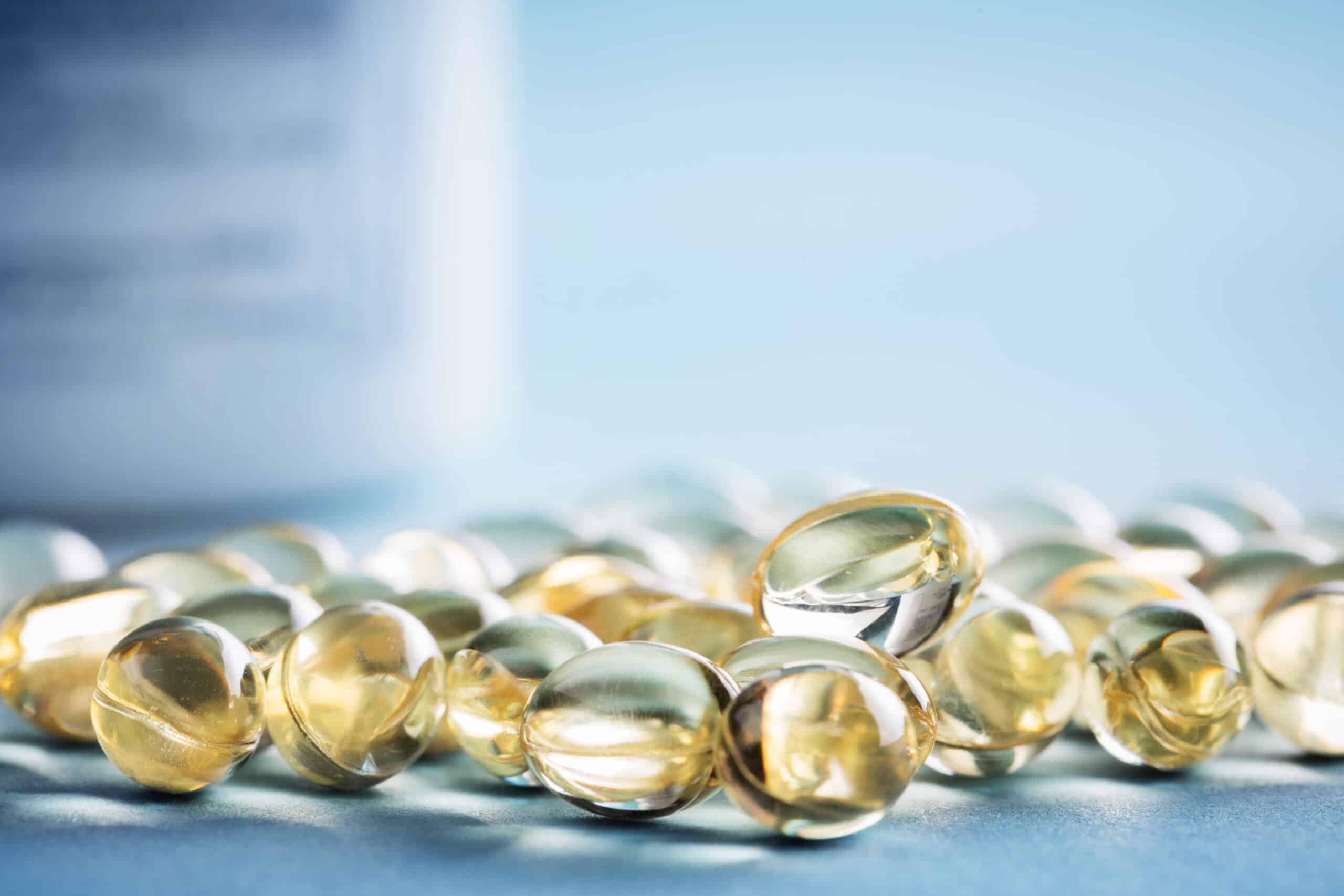 Vitamin D laying on the table with prescription bottle behind them. Supplements pills.