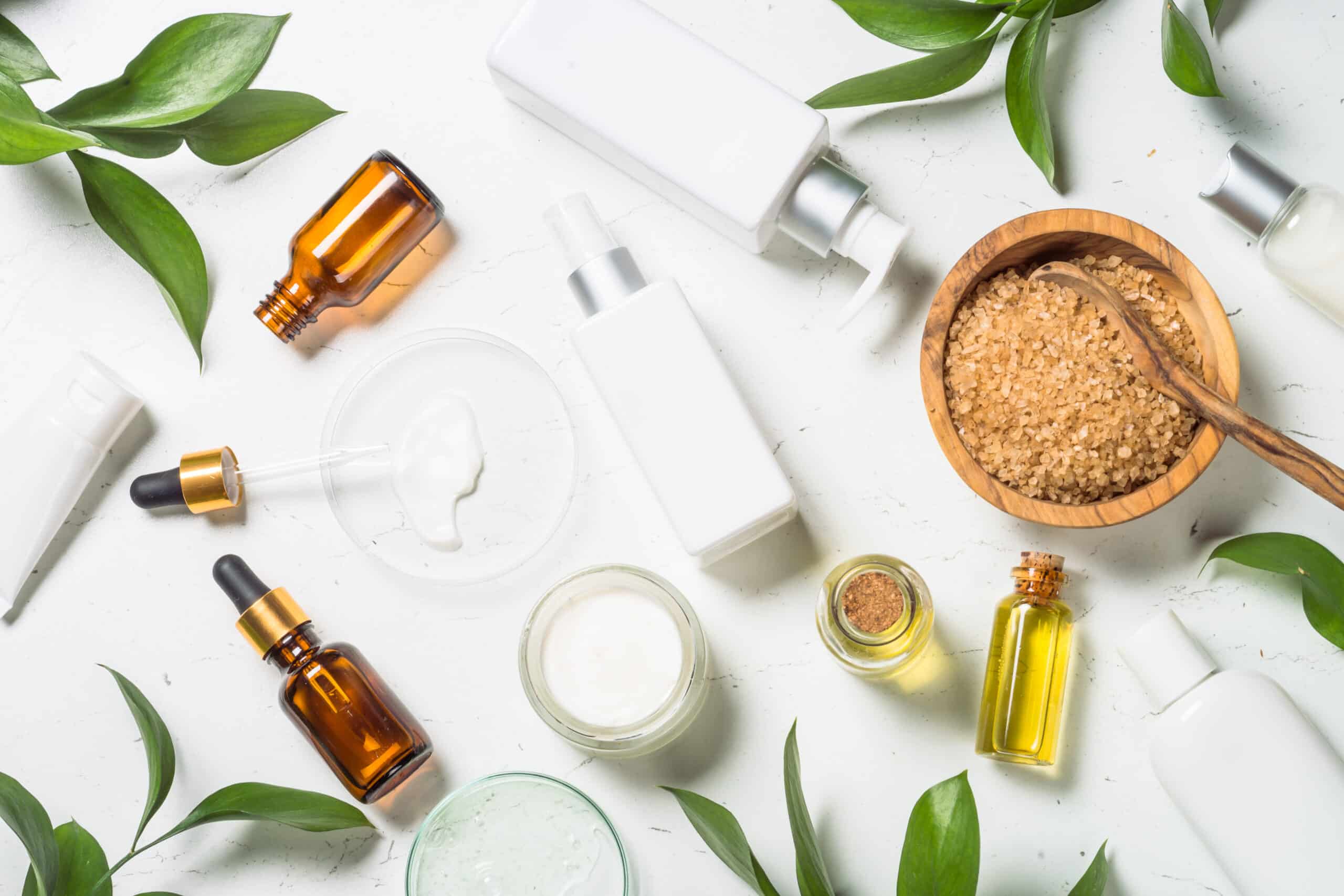 Homemade Cosmetic laboratory. Cosmetic bottles, cream, serum, sea salt and essential oils at white table. Flat lay image.