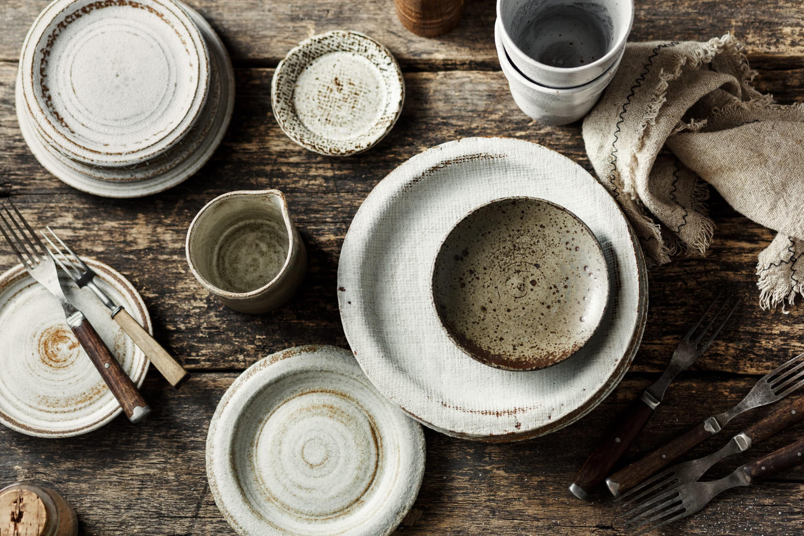 Empty ceramic set and vintage forks on a dark background. Handmade ceramic set. Top view.