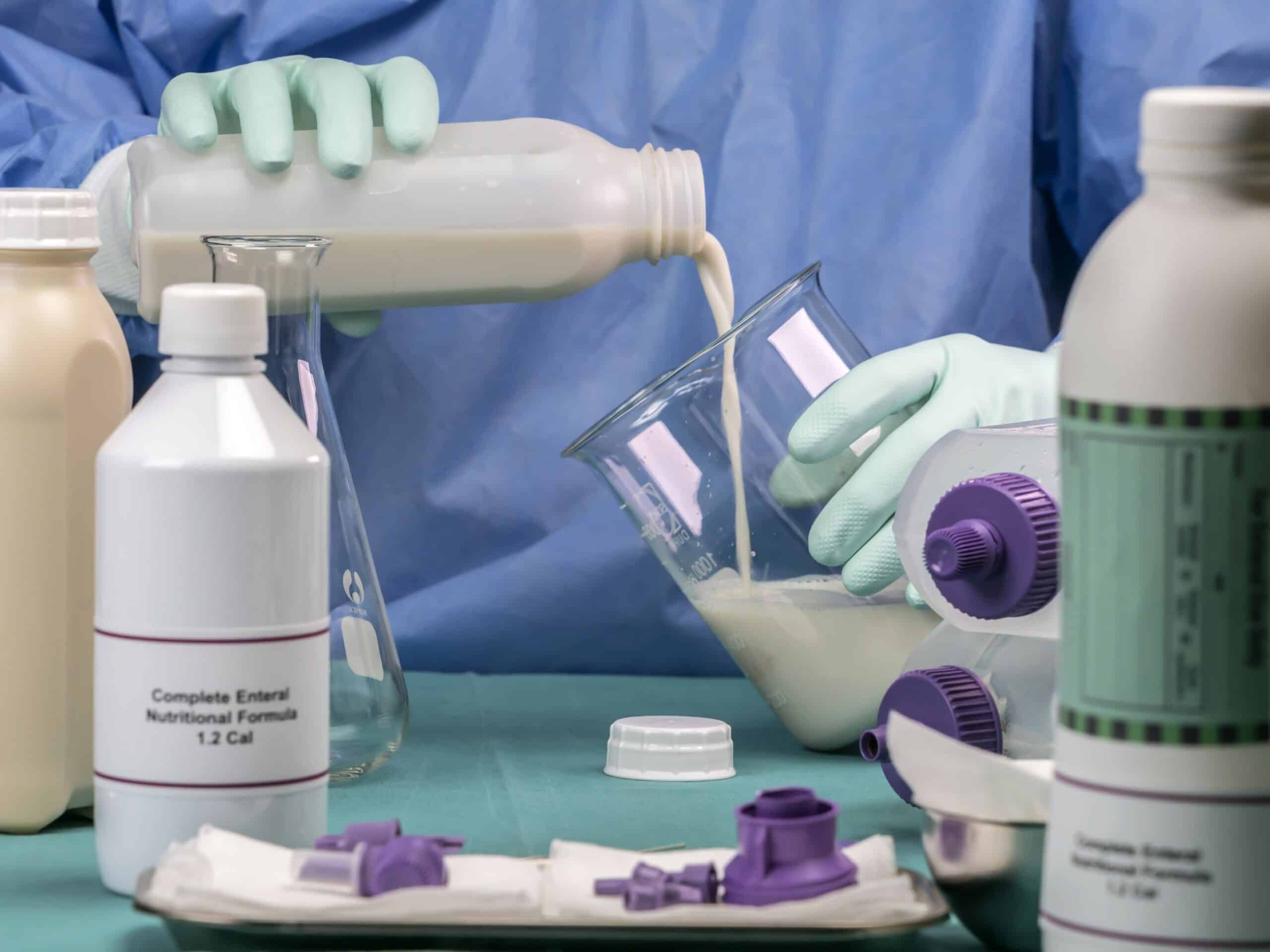 Nurse filling bottle supply in team of enteral nutrition, palliative care in hospital, conceptual image
