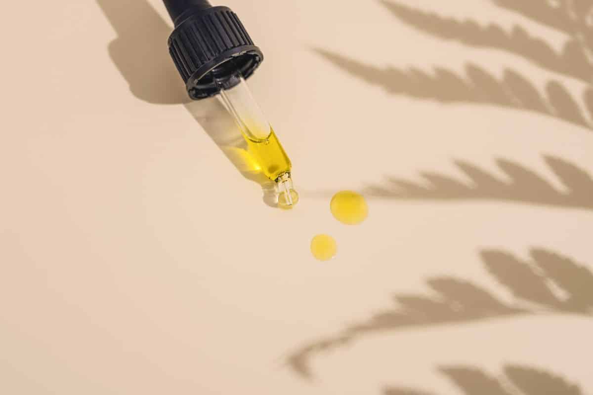 Pipette, die ein goldenes, mit Vitamin C angereichertes Gesichtsöl abgibt und dessen antioxidative und aufhellende Eigenschaften hervorhebt.