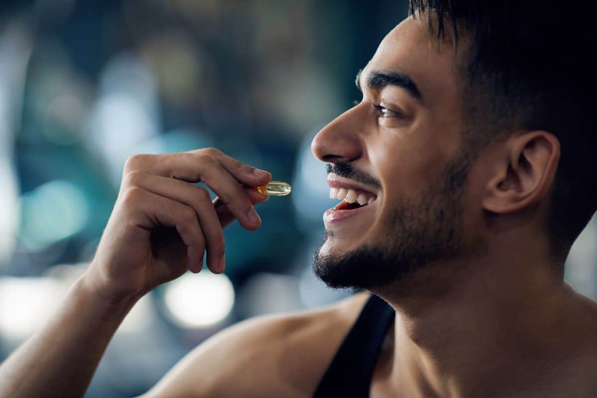 Ein Mann, der eine Nahrungsergänzungspille einnimmt und damit sein Engagement für die Erhaltung seiner Gesundheit und seines Wohlbefindens demonstriert.