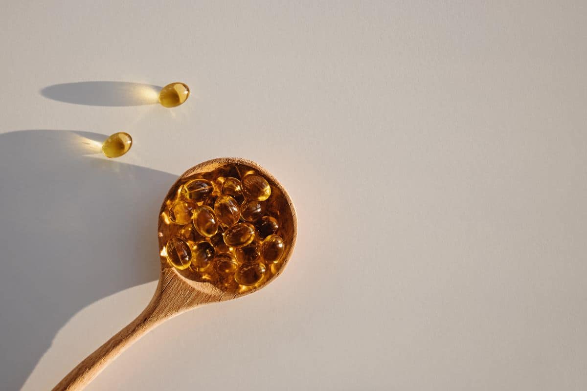 Ein Nahaufnahmebild von Vitamin-D3-Kapseln mit ihrem charakteristischen goldenen Farbton, ordentlich auf einem einfachen, hellen Hintergrund angeordnet, was ihre gesundheitliche Bedeutung betont.