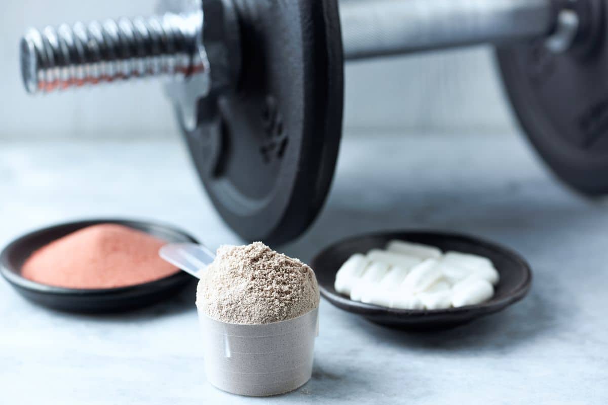 Ein Behälter mit Kreatinpulver und einem Löffel, der häufig von Sportlern und Fitnessbegeisterten zur Verbesserung der Muskelkraft und Trainingsleistung verwendet wird.