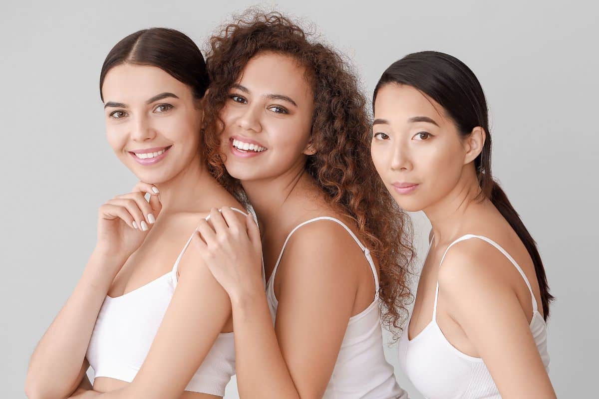 Drei Frauen unterschiedlichen Aussehens stehen zusammen und zeigen Einheit und Kameradschaft.