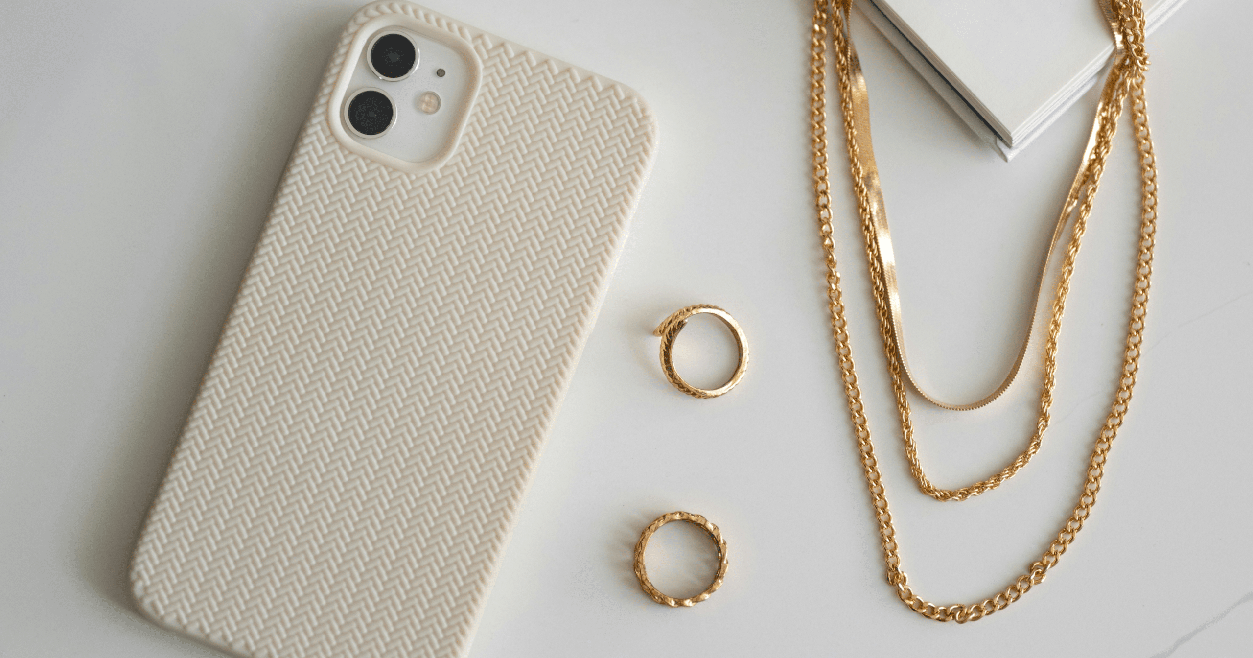Jewelry Trends: A phone next to two rings and a layered necklace.