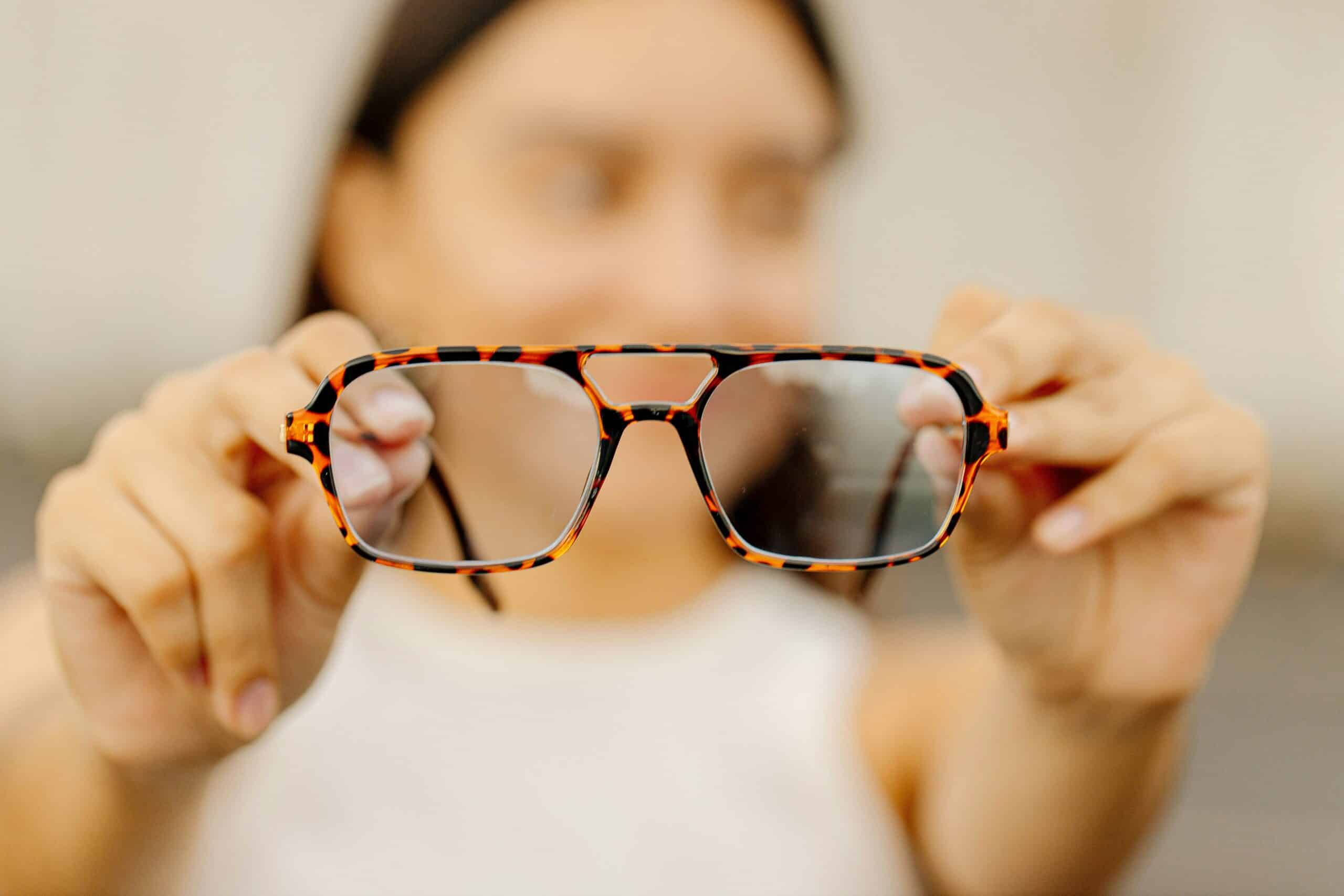 Brillenhersteller: Eine Person, die eine Korrektionsbrille vor sich hält.