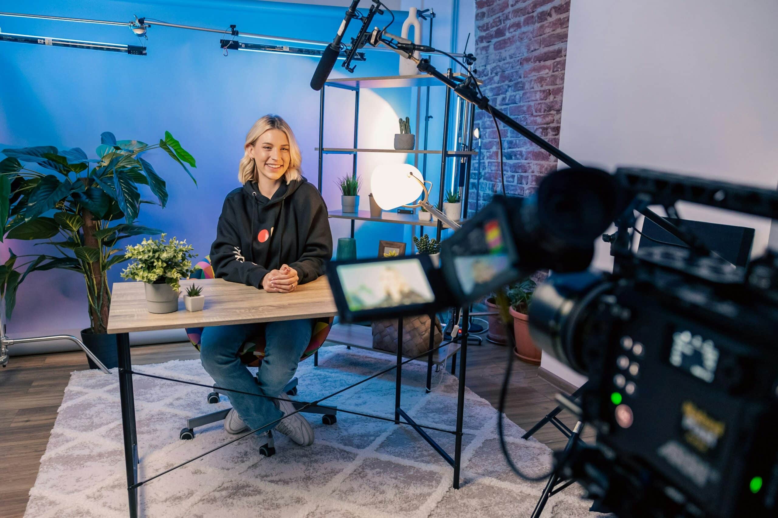 A woman sitting at a desk in front of a camera recording a video.