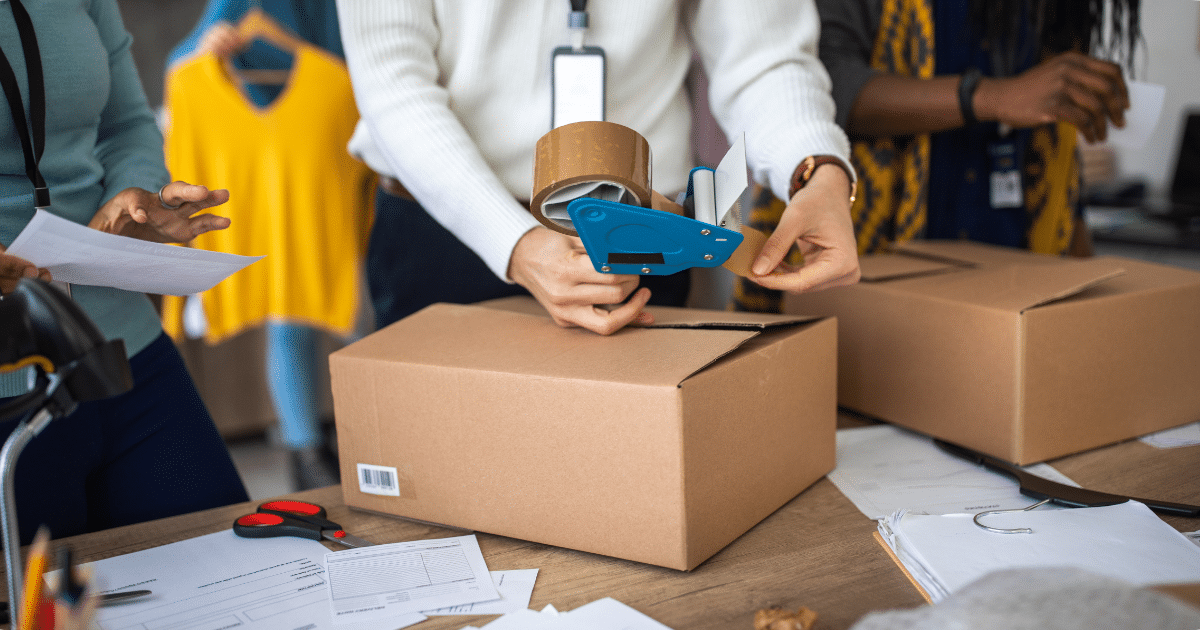 Someone packaging a box of company merchandise