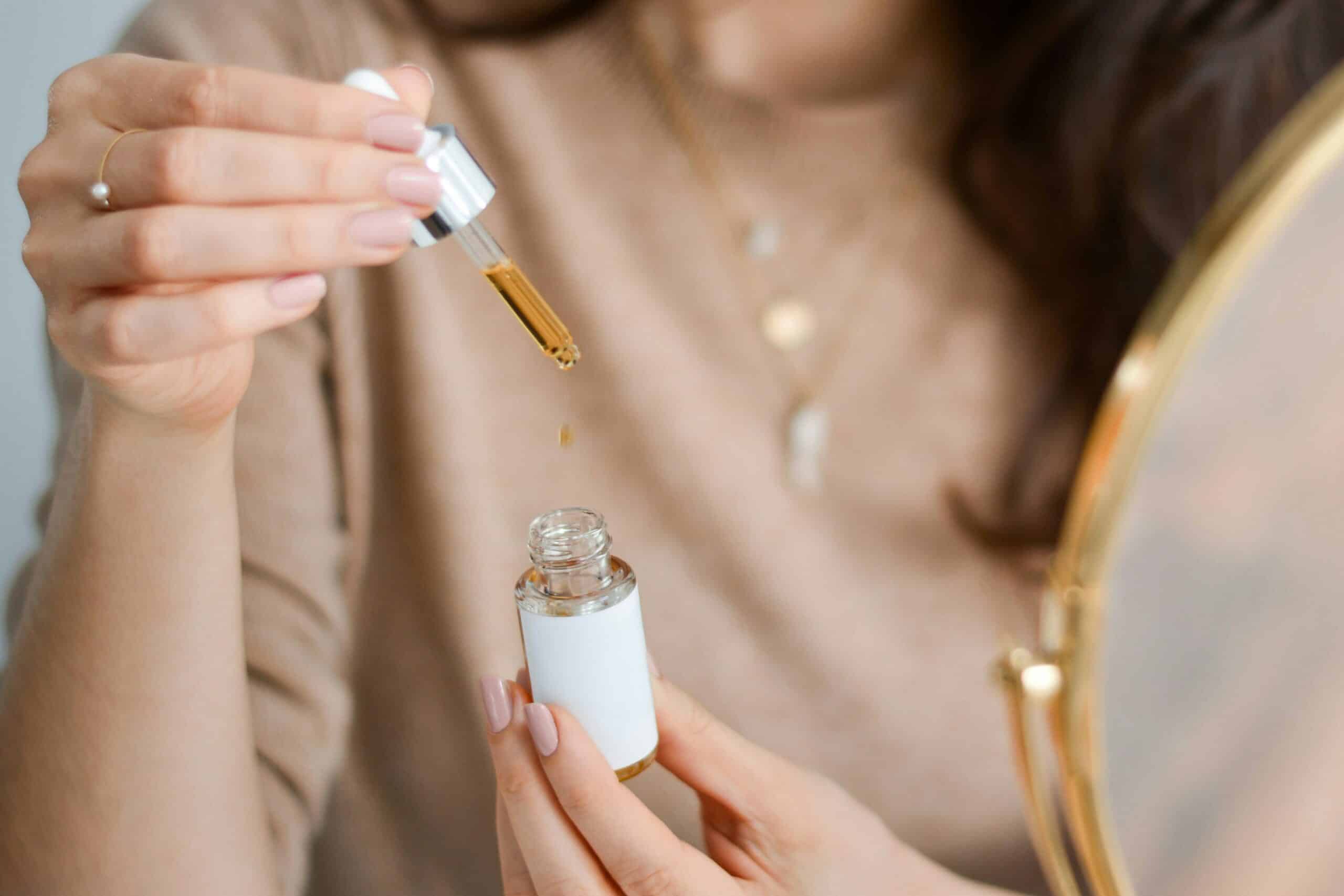 A woman holding a dropper of essential oil.