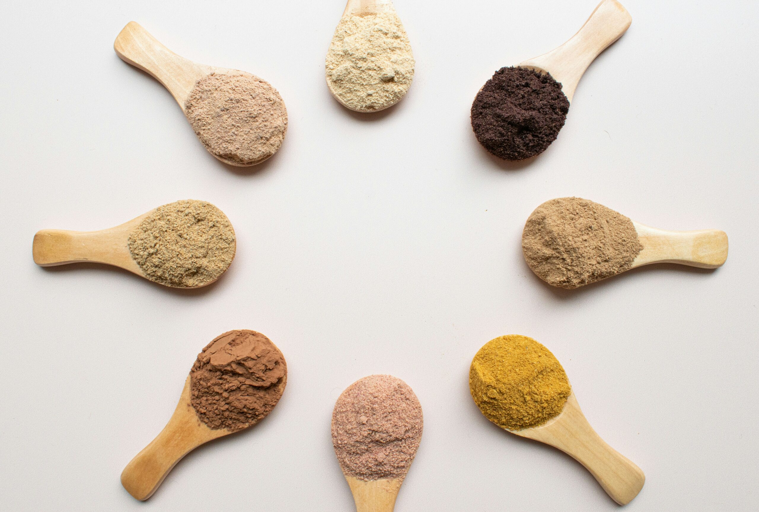 Various (8) supplements powders on spoons in a circle.