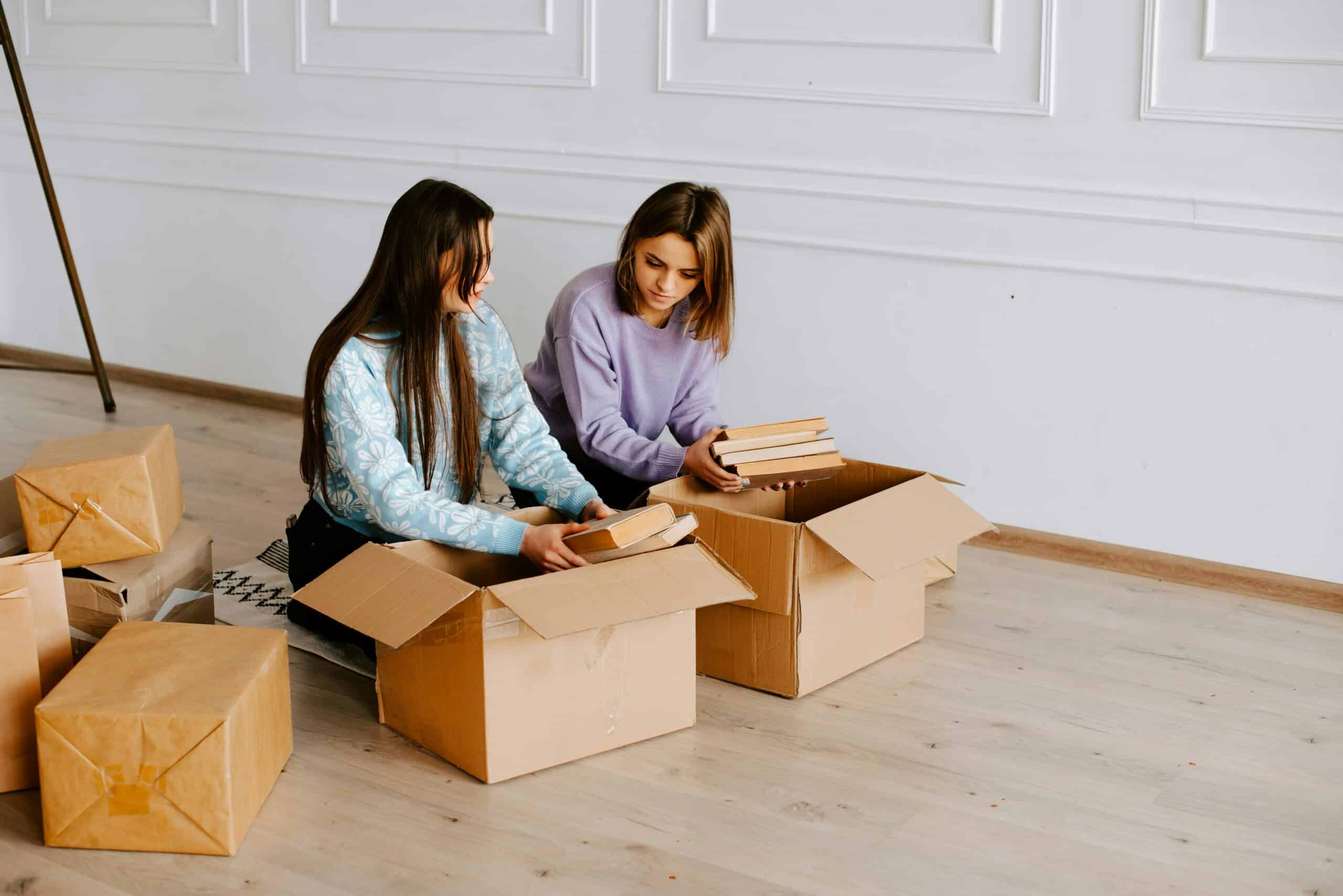 Product sourcing - Two women sit and sort through boxes together.