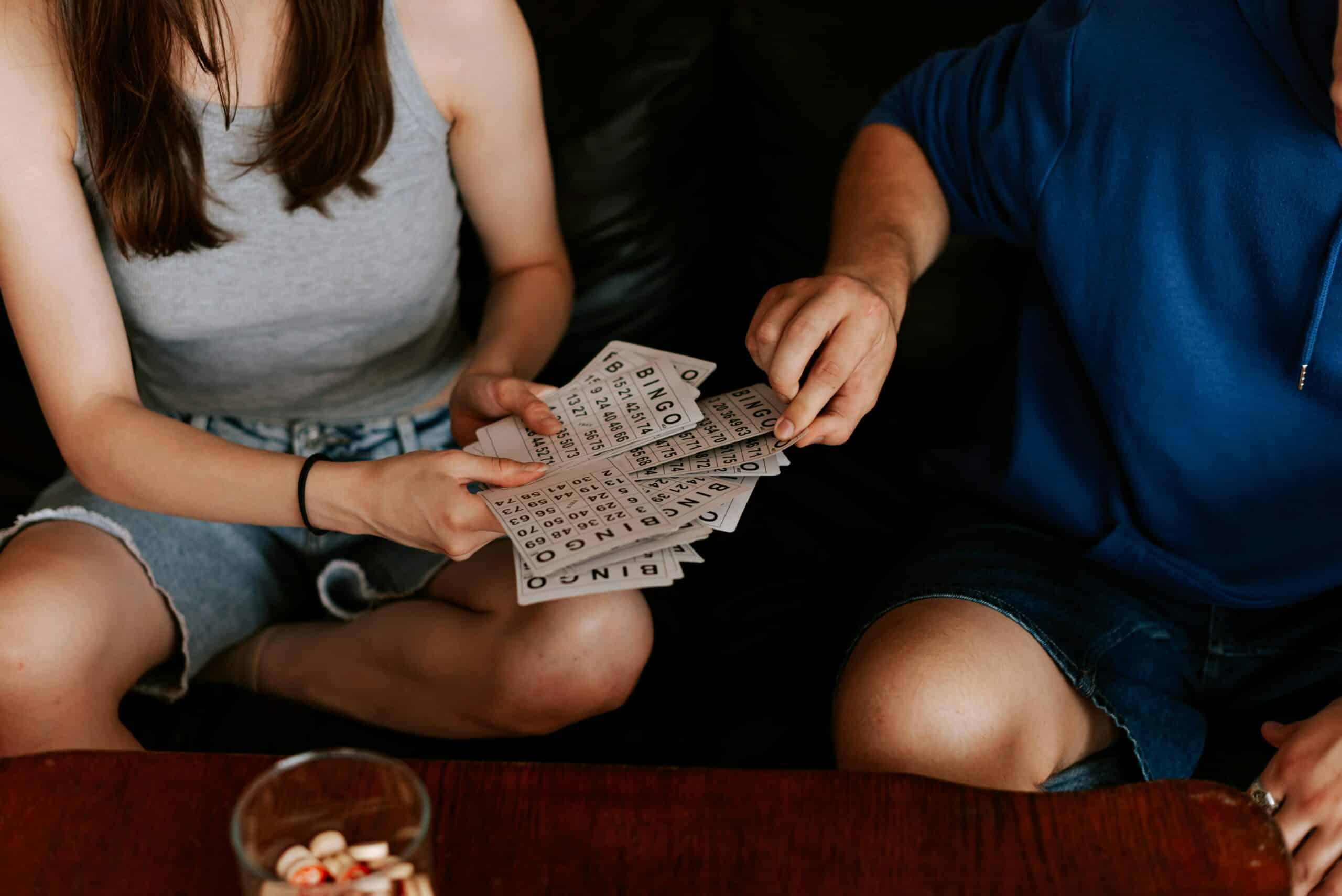 Eine Person hält verschiedene Bingokarten und bietet sie einer anderen Person an.