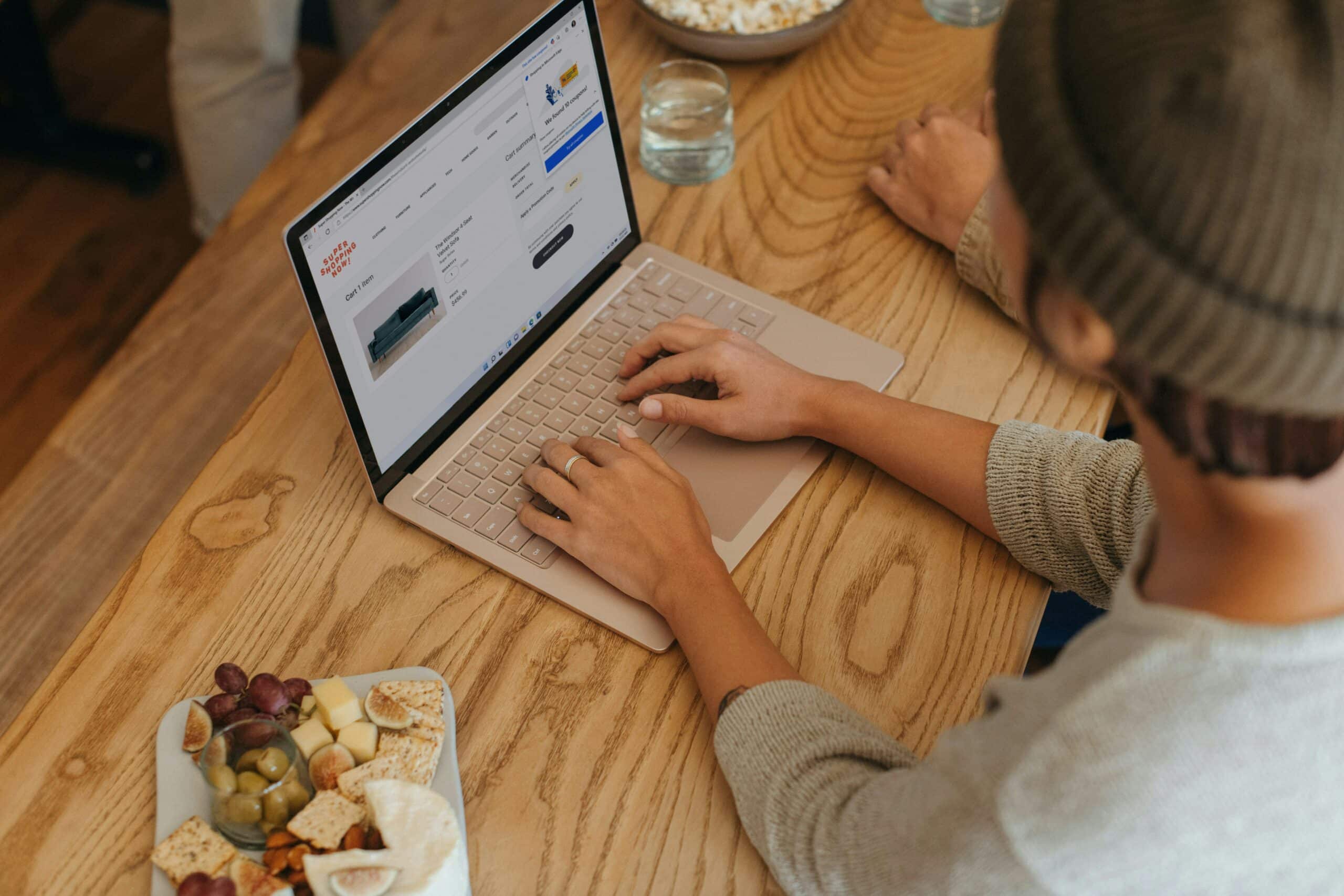 Eine Person tippt an einem Tisch auf ihrem Laptop, um Großhandelswaren zu finden.