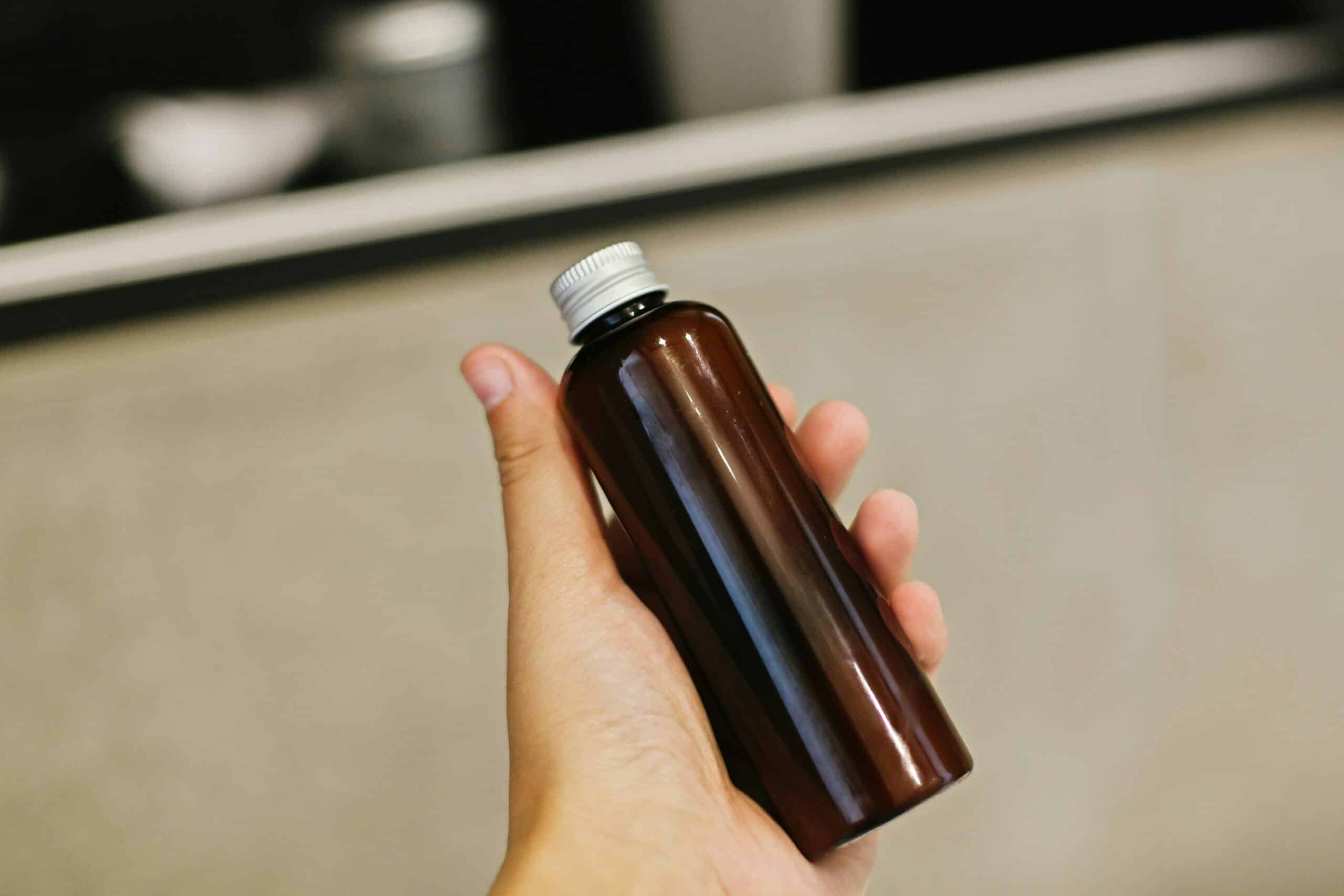 Eine Person, die ein Hautpflegeprodukt wie eine Flasche Serum oder Reiniger hält.